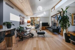Light-filled Australian living room by Coys Constructions featuring timber flooring, modern lounge seating, and large windows with garden views.