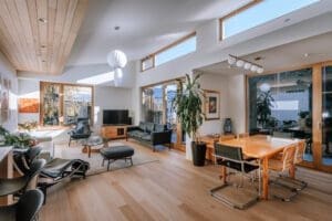 Open-plan living and dining space by Coys Constructions with timber flooring, large windows, and modern Australian design.