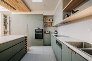 Modern Australian kitchen by Coys Constructions featuring sage green cabinetry, open shelving, and minimalist design.