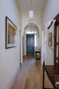 Classic hallway by Coys Constructions featuring timber floors, heritage archway, and a bold navy front door.