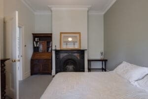 Classic bedroom by Coys Constructions with ornate fireplace, antique furnishings, and soft neutral palette.