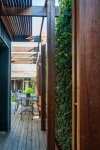 MARIAN HAWTHORN Modern timber pergola by Coys Constructions with outdoor dining area and vertical garden privacy wall.